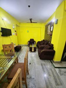 a yellow living room with couches and a tv at mahitra beautiful homestay in Patna