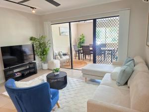 a living room with a couch and a television at Allure at The Edge 3brm luxury apartment with coffee machine and 2 pools! in Cairns North