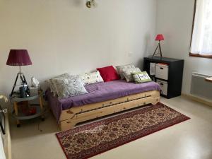 a bedroom with a bed with purple sheets and pillows at Gîte Soye in Eauze