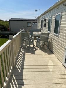 una terraza con 2 bancos y una mesa en una casa en Your Happy Place - 8 Berth Caravan 5 minutes from lovely sandy beach, en Heacham