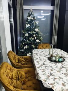 ein Weihnachtsbaum in einem Zimmer mit einem Tisch und Stühlen in der Unterkunft Premium Penthouse in Keszthely