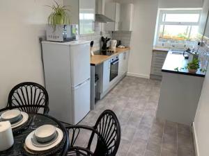 a kitchen with a table and chairs and a refrigerator at Cartref 2 Double Bed Apartment Nebo Dogs Welcome in Amlwch
