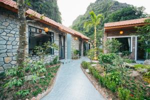 una casa con una pasarela junto a un edificio en Tràng An Riverbank Homestay, en Nguyên Ngoại