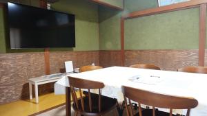 a conference room with a table with chairs and a flat screen tv at PANARI guest house NISHIHONMACHI in Ube