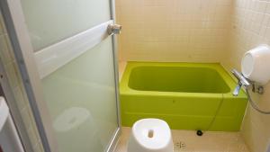 a bathroom with a green tub and a toilet at PANARI guest house NISHIHONMACHI in Ube +1 photo