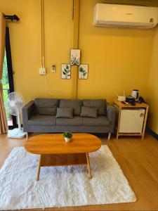 uma sala de estar com um sofá e uma mesa de centro em บ้านสวนผาหมี em Ban Nong Chaeng