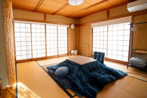a bedroom with a large bed in a room with windows at Denim Lodge Nest in Kurashiki