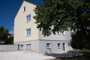 ein weißes Haus mit einem Baum davor in der Unterkunft W&P Living Wohnung mit Ausblick - Parkplatz in Biberbach