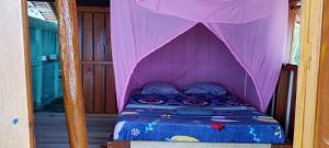 a bed in a pink tent in a room at Nyanderos homestay in Poelau Mansoear