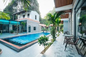 Una piscina con una mesa y sillas al lado de una casa. en Tràng An Riverbank Homestay, en Nguyên Ngoại