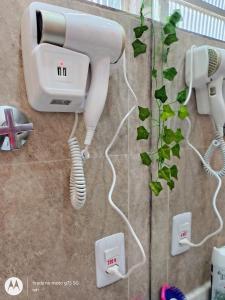a hair dryer and a phone on a wall at Apartamento confortável José menino com estacionamento in Santos