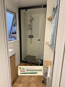 a glass shower in a bathroom with a sign on the door at L'Escapade Seignossaise in Seignosse