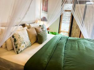 Rowinrich Cottages في إيلا: سرير أخضر مع ستائر ووسائد في غرفة النوم