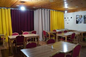 a restaurant with wooden tables and chairs and yellow curtains at Petra sharing room in Petra