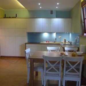 a kitchen with a wooden table and white cabinets at Apartament Hania - Krynica Morska in Krynica Morska