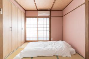 a bedroom with a white bed and a window at 蛮子民宿 金閣寺 in Kyoto