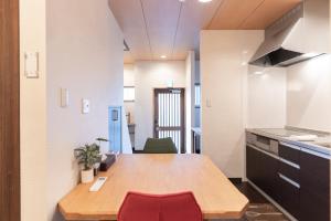 a kitchen with a wooden table and a red chair at 蛮子民宿 金閣寺 in Kyoto