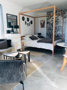 a bedroom with a bed and a couch and tables at Bel Air Studios-Terrasse couverte-Jardinet-Vue Pont de Normandie-Parking privé in Honfleur