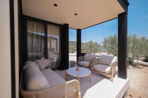 a porch with a couch and chairs and a table at Jazine BeachVilla5 in Tisno +12 photos