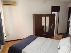 Un dormitorio con una cama y un armario de madera. en VERA's TOWERS, en Accra
