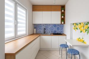 una cocina con armarios blancos y azulejos azules y blancos en Cozy M3 at Pojezierska Street, en Łódź