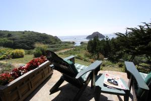 2 Stühle und ein Tisch auf dem Balkon mit Meerblick in der Unterkunft Elk Cove Inn & Spa in Elk