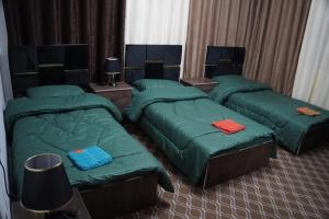 three beds in a room with green comforters at Petra cabin Roof top hostel in Wadi Musa