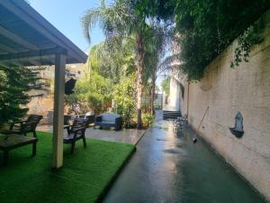 a patio with chairs and a table and palm trees at pinsker apartment city center in Petaẖ Tiqwa