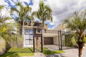 马林加Casa Munique Maringa的围栏前有棕榈树的房子