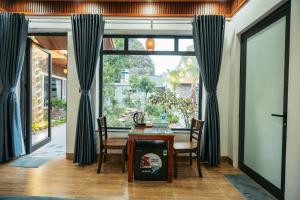 Un comedor con una mesa y un gran ventanal. en Tràng An Riverbank Homestay, en Nguyên Ngoại