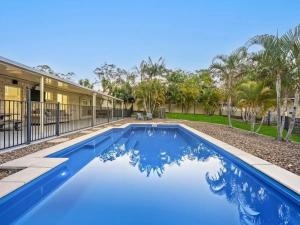 Park RidgeLuxury Retreat with Resort Pool, Home Cinema的棕榈树环绕的房子前的游泳池