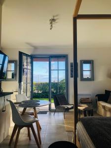 a living room with a bed and a table and chairs at Bel Air Studios-Terrasse couverte-Jardinet-Vue Pont de Normandie-Parking privé in Honfleur