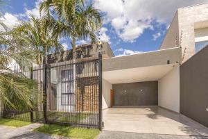 una casa con un cancello di fronte a una palma di Casa Munique Maringa a Maringá