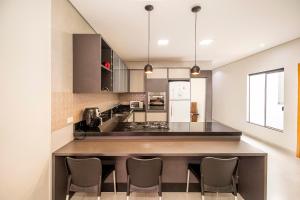 una cucina con bancone e sedie di Casa Munique Maringa a Maringá