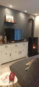 Una sala de estar con un televisor grande y una chimenea. en Entre 2 Châteaux, en Onzain