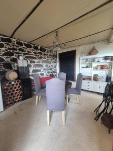 a dining room with a table and chairs and a stone wall at Quinta do Ribeiro Real in Câmara de Lobos
