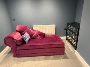 a purple couch with pillows on it in a room at The Ship Inn's Mill Cottage - Weavers Way in Gatehouse of Fleet +25 photos