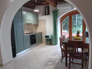 eine Küche mit grünen Schränken und einem Tisch mit Stühlen in der Unterkunft Casa Chiasso in Gabbro