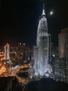 Sky Suites Luxury apartment by KL في كوالالمبور: ناطحة سحاب مضاءة في مدينة في الليل