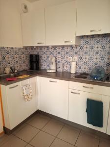 una cucina con armadi bianchi e piastrelle blu di Villa Les Margats - A deux pas de la mer - Terrasse et Parking a Bray-Dunes