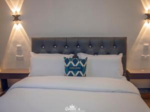 埃尔多雷特Queens Premier Suites in Eldoret Opposite Tamasha Village的一张大床,配有黑色床头板和白色枕头