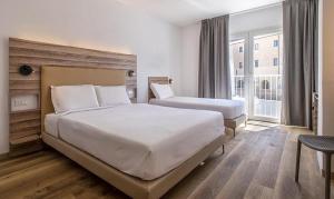 a hotel room with two beds and a window at B&B HOTEL Sassari in Sassari