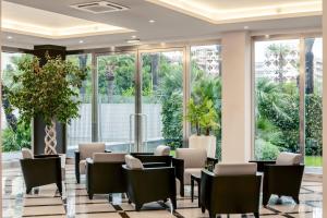 B&B HOTEL Bari Rondò في باري: غرفة انتظار مع طاولات وكراسي ونوافذ كبيرة