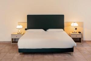 B&B HOTEL Bari Rondò في باري: غرفة نوم بها سرير كبير وطاولتين جانبيتين