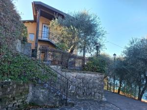 a house with a stone wall and a fence at Madonna Dell'Aiuto True View Olivo in Brenzone sul Garda