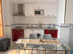 a kitchen with a glass table with chairs and a microwave at Apartamentos Silleria - A 4 min de la Catedral de Granada in Granada