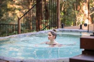 a woman is swimming in a swimming pool at Kanimbia Cottages in Coolabine