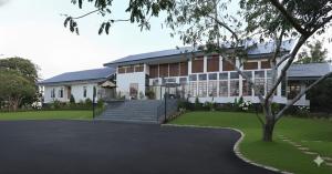 a large building with a staircase in front of a yard at PhuKasa Valley Maesot -Wellness Resort in Ban Mae Kasa