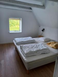two beds in a white room with a window at Kjærgaarden B&B - Bed & Breakfast i Havnsø in Føllenslev