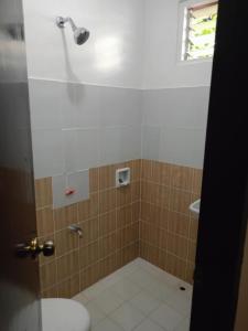 a bathroom with a shower with a toilet and a window at Cabugao Bed & Breakfast and Dorm in El Nido